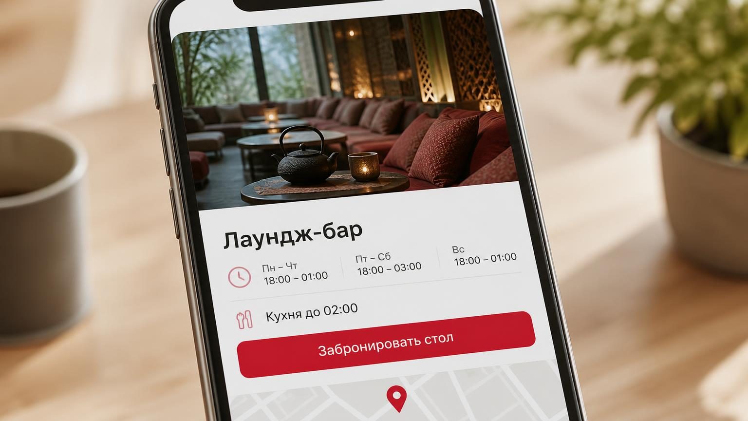 Экран смартфона крупно: карточка заведения в картографическом сервисе, на обложке — зал с низкими диванами и чайником, ниже строки с часами работы. Надписи: заголовок «Лаундж-ба…